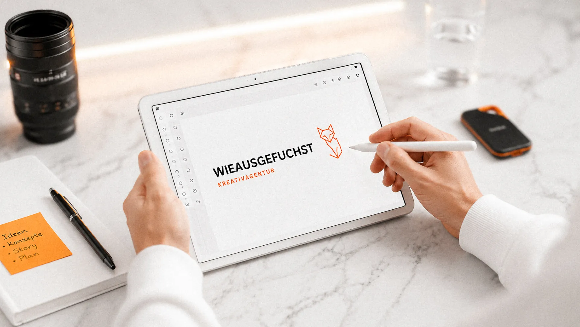 Wieausgefuchst Kreativagentur: Logo-Entwurf auf dem Tablet, daneben Notizen mit Ideen, Konzepten, Story und Plan